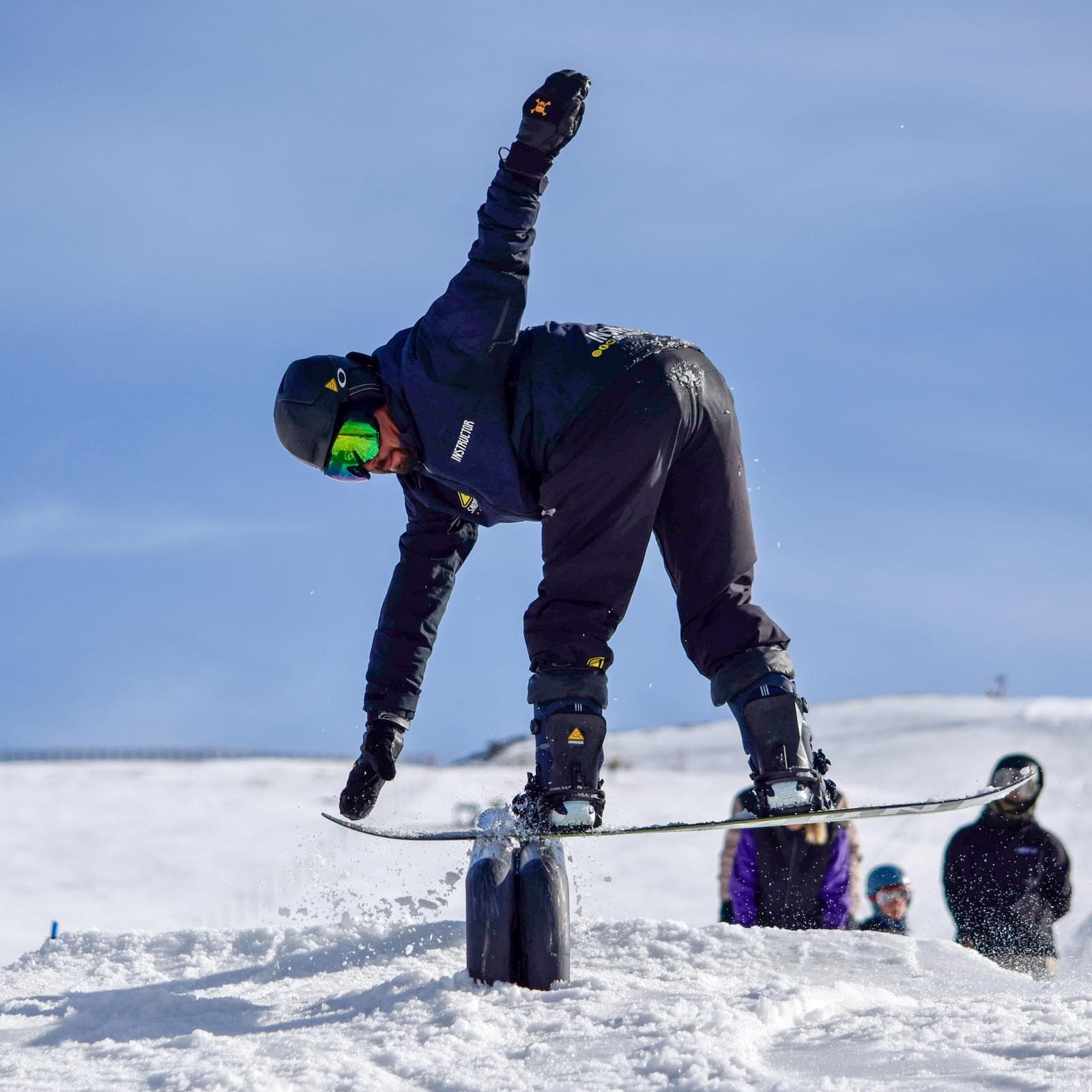 Monitor de Snow Riders Academy haciendo un truco de snowboard sobre un módulo